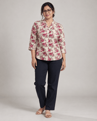Woman wearing Vintage Rose beige floral cotton V-neck top with navy trousers, front view