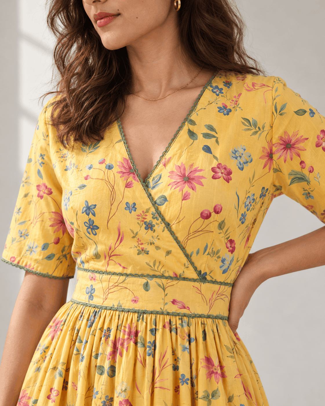 Close-up of wrap V-neck and green lace trim on yellow wildflower print cotton dress