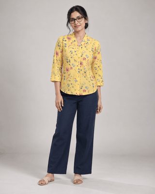 Woman wearing Marigold Meadow yellow floral cotton V-neck top with navy trousers, front view